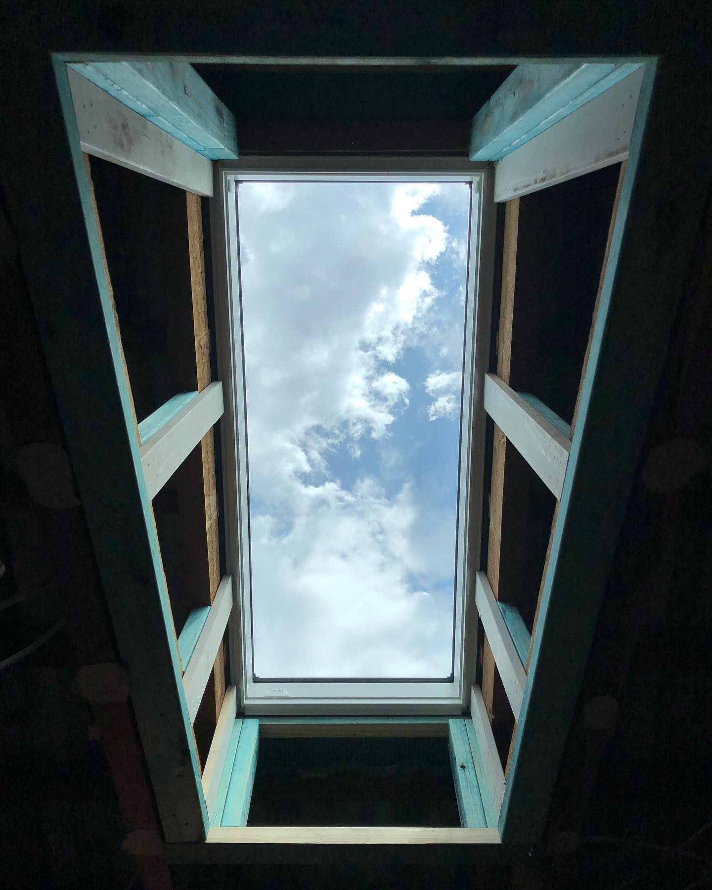 Skylight installation — view through new roof frame to blue sky